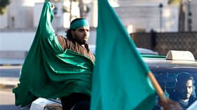 Un partisan de Mouammar Kadhafi dans un cortège de voitures dans le centre de Tripoli. Des tirs ont retenti dimanche avant l'aube dans la capitale libyenne, où la télévision publique, citant une source militaire, affirme que les forces régulières ont repr