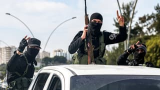 Les forces de sécurité fidèles au gouvernement syrien intérimaire font un geste à l'arrière d'un véhicule circulant sur une route de la ville de Lattaquié, dans l'ouest de la Syrie, le 9 mars 2025.