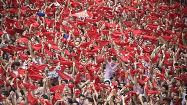 Des participants agitent leurs foulards rouges lors de la cérémonie d'ouverture du "Chupinazo" (fusée de départ) qui marque le coup d'envoi des fêtes taurines de la San Fermin devant la mairie de Pampelune, dans le nord de l'Espagne, le 6 juillet 2024.