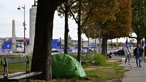 Des passants près d'une tente de personnes sans abris près de la place de la Concorde à Paris le 18 octobre 2023.