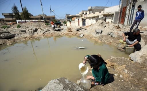 Des habitants de Mossoul remplissent des bidons d'eau, le 6 avril 2017 en Irak Des habitants de Mossoul remplissent des bidons d'eau, le 6 avril 2017 en Irak