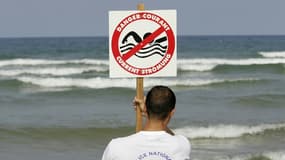 Un CRS maître-nageur-sauveteur installe un panneau indiquant la présence de courants de baïne, le 21 juillet 2004 sur la plage de Lacanau  