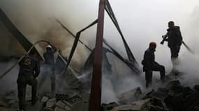 Des Casques blancs syriens éteignent un incendie provoqué par des frappes aériennes du régime sur la ville rebelle de Hamouria, dans les environs de Damas, le 21 mars 2017