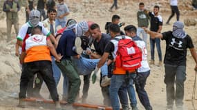Des manifestants palestiniens et des secouristes évacuent un blessé lors de heurts avec l'armée israélienne à Beita, en Cisjordanie occupée, le 23 juillet 2021