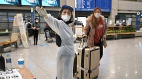 Une hôtesse (au centre) en tenue de protection anti-Covid informe une voyageuse dans le hall d'arrivée de l'aéroport international d'Incheon (Corée du Sud), le 30 novembre 2021