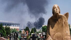 De la fumée noire s'élève au dessus de l'aéroport de Donetsk, vu depuis un cimetière.