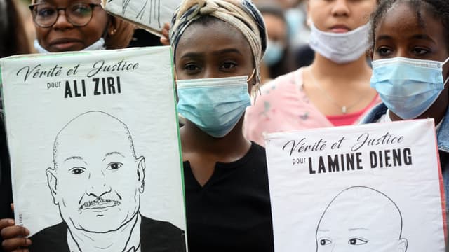 Manifestantes portant des pancartes en mémoire notamment de Lamine Dieng.
