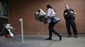 Une femme dépose un bouquet de fleurs devant le commissariat de police de Roubaix (Nord) en homme aux policiers tués dans un accident de la route, le 21 mai 2023