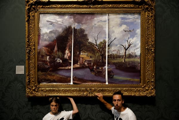 Des militants du groupe "Just Stop Oil", les mains collées au cadre du tableau "The Hay Wain" de John Constable, mais recouvert d'une version  comprenant des routes et des avions, protestent contre l'utilisation des combustibles fossiles, à la National Gallery de Londres, le 4 juillet 2022.