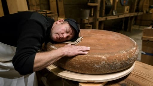 Le fromager Beat Wampfler pose sa tête sur une meule d'emmental dont l'affinage se déroule en musique, le 19 octobre 2018 à Berthoud, en Suisse