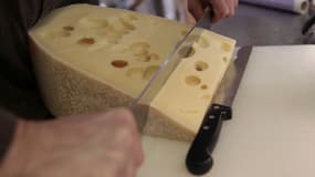 Un vendeur de fromages coupe une tranche d'emmental