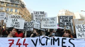 Des femmes dénoncent sur des pancartes les victimes de violences conjugales en France, lors d'une manifestation le 8 mars 2022 à Paris pour la journée internationale pour les droits des femmes