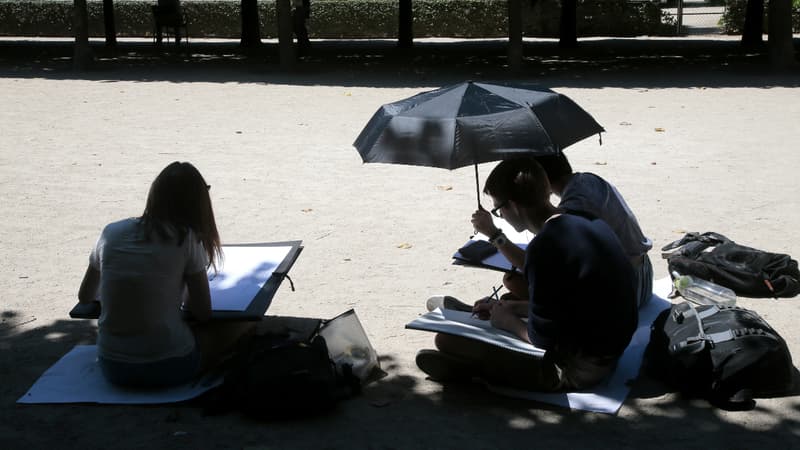 Des jeunes gens se rafraîchissent à l'ombre dans l'enceinte du Palais Royal à Paris, le 6 juillet 2015.