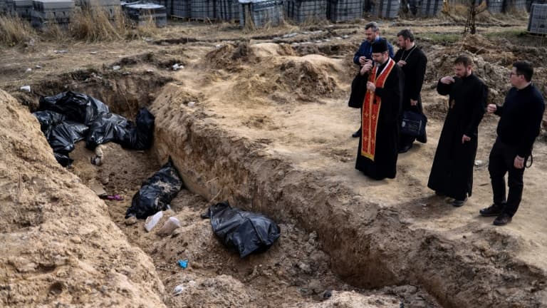 Des prêtres prient devant une fosse commune avec de nouveaux cadavres, dans la petite ville ukrainienne de Boutcha, le 7 avril 2022