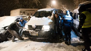 Des automobilistes tentent de déplacer un camion coincé dans la neige, le 7 février 2018 à Bièvres (Essonne)