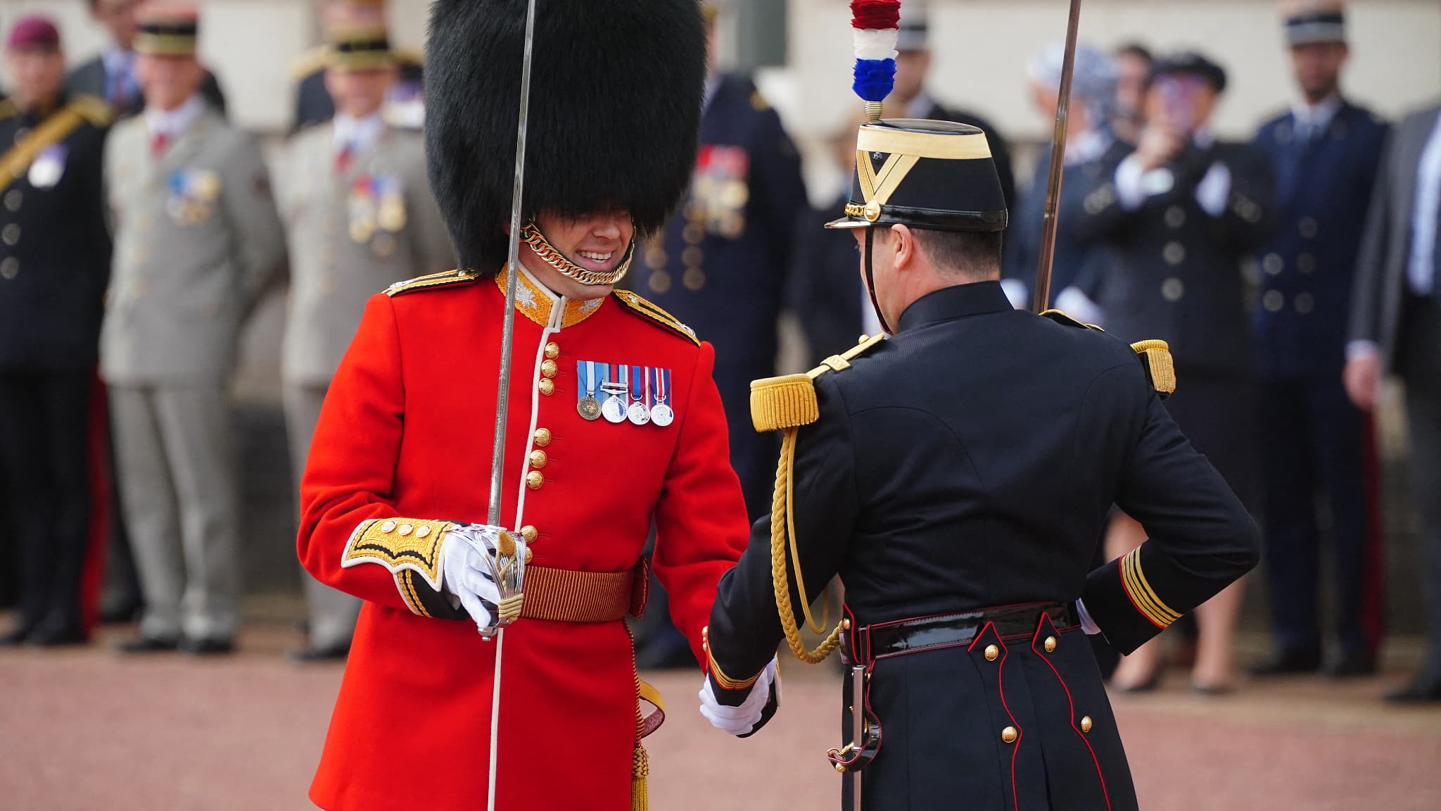 Un garde royal britannique et un gendarme de la Garde républicaine française se serrent la main à l'occasion d'une séance spécial de relève de la garde au palais de Buckingham, à Londres, le 8 avril 2024. Un garde royal britannique et un gendarme de la Garde républicaine française se serrent la main à l'occasion d'une séance spécial de relève de la garde au palais de Buckingham, à Londres, le 8 avril 2024.