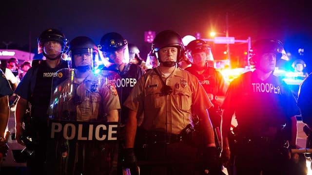 La police de Saint-Louis est positionnée sur Florisant Avenue, à Ferguson, pendant les manifestations d'hommage à Michael Brown, le 9 août 2014.