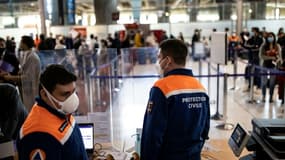 Des membres de la Protection civile contrôlent des voyageurs dans le cadre des mesures sanitaires à l'aéroport Roissy Charles de Gaulle, le 25 avril 2021
