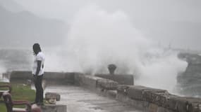 Un homme regarde les vagues se briser contre les murs du front de mer de Kingston, le 27 octobre 2025.