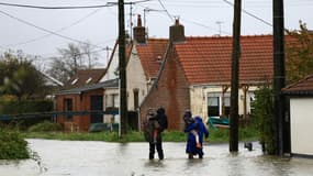 Des personnes marchent dans une rue inondée au Doulac, près de Saint-Omer, le 14 novembre 2023, dans le Pas-de-Calais