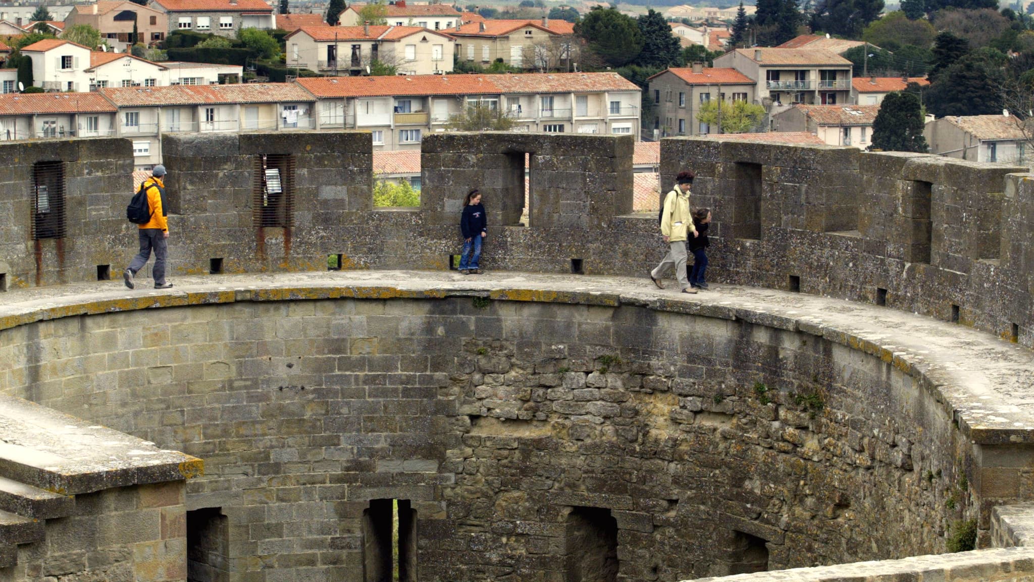 Des touristes se promènent sur les remparts de la cité de Carcassonne, le 13 avril 2004. La cité de Carcassonne, un des monuments les plus visités de France, a été rénovée à partir de 1844 par l'architecte Viollet-le-Duc, et est inscrite par l'UNESCO sur la liste du patrimoine mondial de l'Humanité. Des touristes se promènent sur les remparts de la cité de Carcassonne, le 13 avril 2004. La cité de Carcassonne, un des monuments les plus visités de France, a été rénovée à partir de 1844 par l'architecte Viollet-le-Duc, et est inscrite par l'UNESCO sur la liste du patrimoine mondial de l'Humanité.
