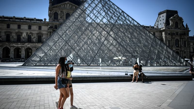 Des touristes masqués devant la Pyramide du Louvre