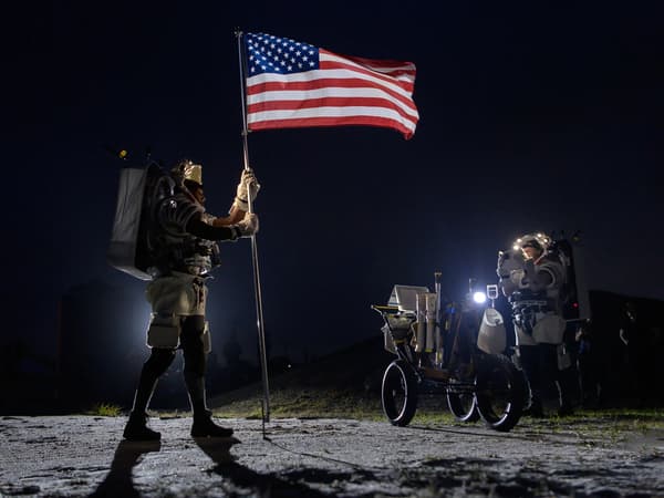 L'astronaute de la NASA Kate Rubins (à droite) prend une photo de l'astronaute de la NASA Andre Douglas (à gauche) alors qu'il lève un drapeau américain lors d'une simulation de marche sur la Lune dans le désert de l'Arizona