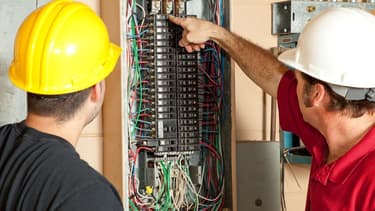 Des électriciens installent un panneau.