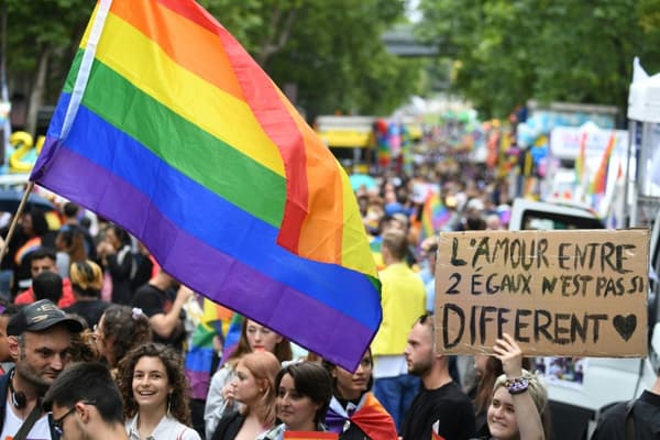 Des participants à la Marche des fiertés à Paris bradissent le drapeau arc en ciel et des banners, le 25 juin 2022