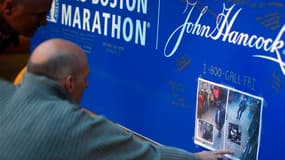 A Boston deux hommes regardent les photos de deux suspects dans l'enquête sur le double attentat à la bombe de Boston diffusées par le FBI jeudi. /Photo prise le 18 avril 2013/REUTERS/Brian Snyder