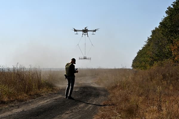 Un Ukrainien contrôle le vol d'un drone transportant un détecteur de métaux pour rechercher des mines près de la ville de Derhachi, dans la région de Kharkiv, le 1er octobre 2023.