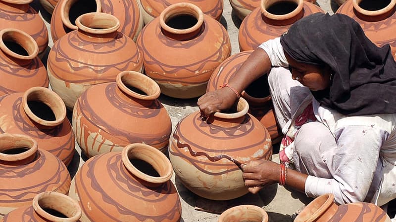 Une indienne met la dernière touche à des pots servant à conserver les aliments.