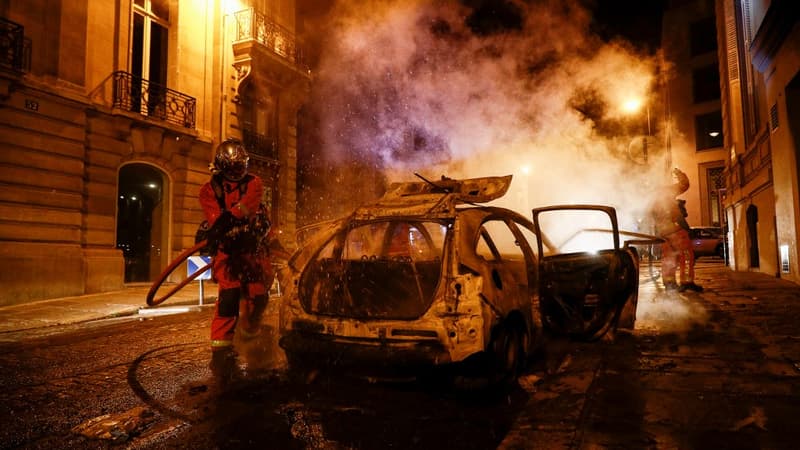 Des pompiers éteigne un feu de voiture dimanche, dans une rue proche des Champs-Élysées