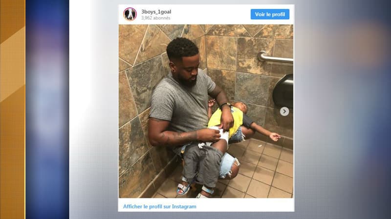 Le père de famille en train d'essayer de changer la couche de son ils dans des toilettes pour hommes.