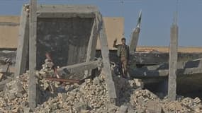 Un milicien chiite fait le signe de la victoire sur les ruines du tombeau de Saddam Hussein.