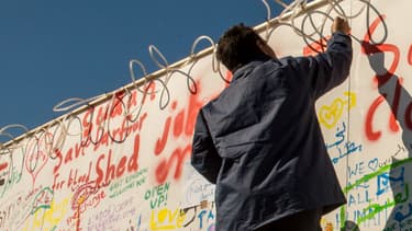 Un migrant inscrit un message sur un mur du terminal de ferry de Calais (photo d'illustration)
