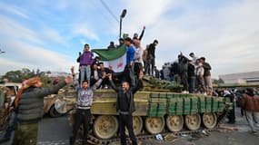 Des habitants célèbrent avec des combattants anti-gouvernementaux la fin du régime de Bachar al-Assad sur la place des Omeyyades à Damas
