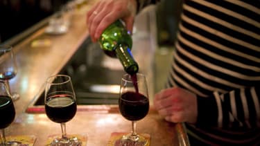 Un homme en train de servir des verres de vin rouge.