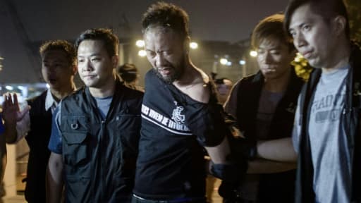 Ken Tsang (c), militant du Parti civique, est emmené par des policiers lors des manifestations pour la démocratie, le 15 octobre 2014 à Hong Kong Ken Tsang (c), militant du Parti civique, est emmené par des policiers lors des manifestations pour la démocratie, le 15 octobre 2014 à Hong Kong