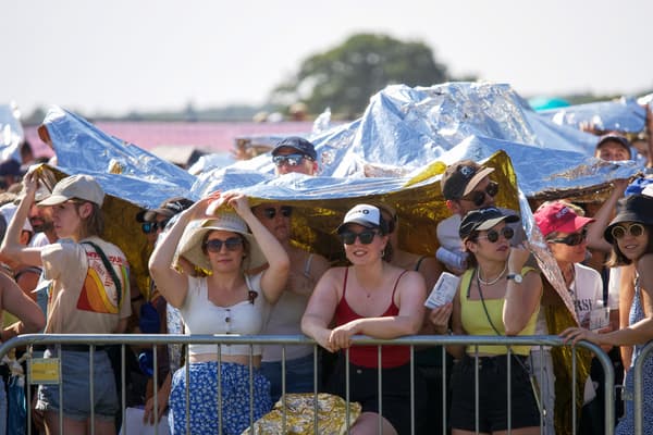 Des personnes se protègent de la chaleur sous des couvertures de survie lors d'un concert au château de Chambord à Chambord, dans le centre de la France, le 8 septembre 2023.