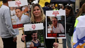Une femme tenant des photos des otages israéliens Or Levy, Eli Sharabi et Ohad Ben Ami.