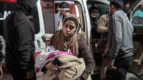 Une femme portant un bébé se précipite au service des urgences de l'hôpital Shuhada al-Aqsa à Al-Zawayda dans le centre de la bande de Gaza, après un bombardement israélien le 1er mars 2024.