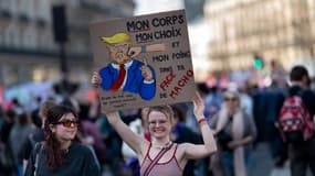 Une manifestante tient une pancarte sur laquelle on peut lire « Mon corps, mon choix et mon poing dans ta gueule de macho » lors d'une manifestation dans le cadre de la Journée internationale des droits des femmes 2025 à Paris, le 8 mars 2025.