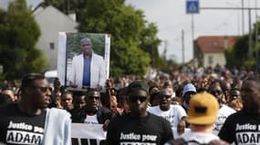 Des manifestants lèvent un portrait d'Adama Traoré en son hommage, en juillet 2018 à Beaumont-sur-Oise. FRANCOIS GUILLOT / AFP