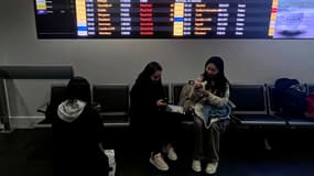 Des passagers attendent que les tableaux des départs de l'aéroport de Manchester indiquent les nombreux vols annulés ou retardés en raison des vents violents provoqués par la tempête Isha