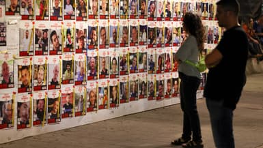 Des personnes regardent des portraits d'otages israéliens, détenus à Gaza depuis l'attaque du 7 octobre, affichés sur un mur à Tel Aviv le 23 avril 2024.