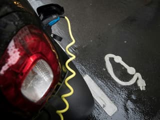 Une voiture électrique branchée à une borne, sur une place de parking.
