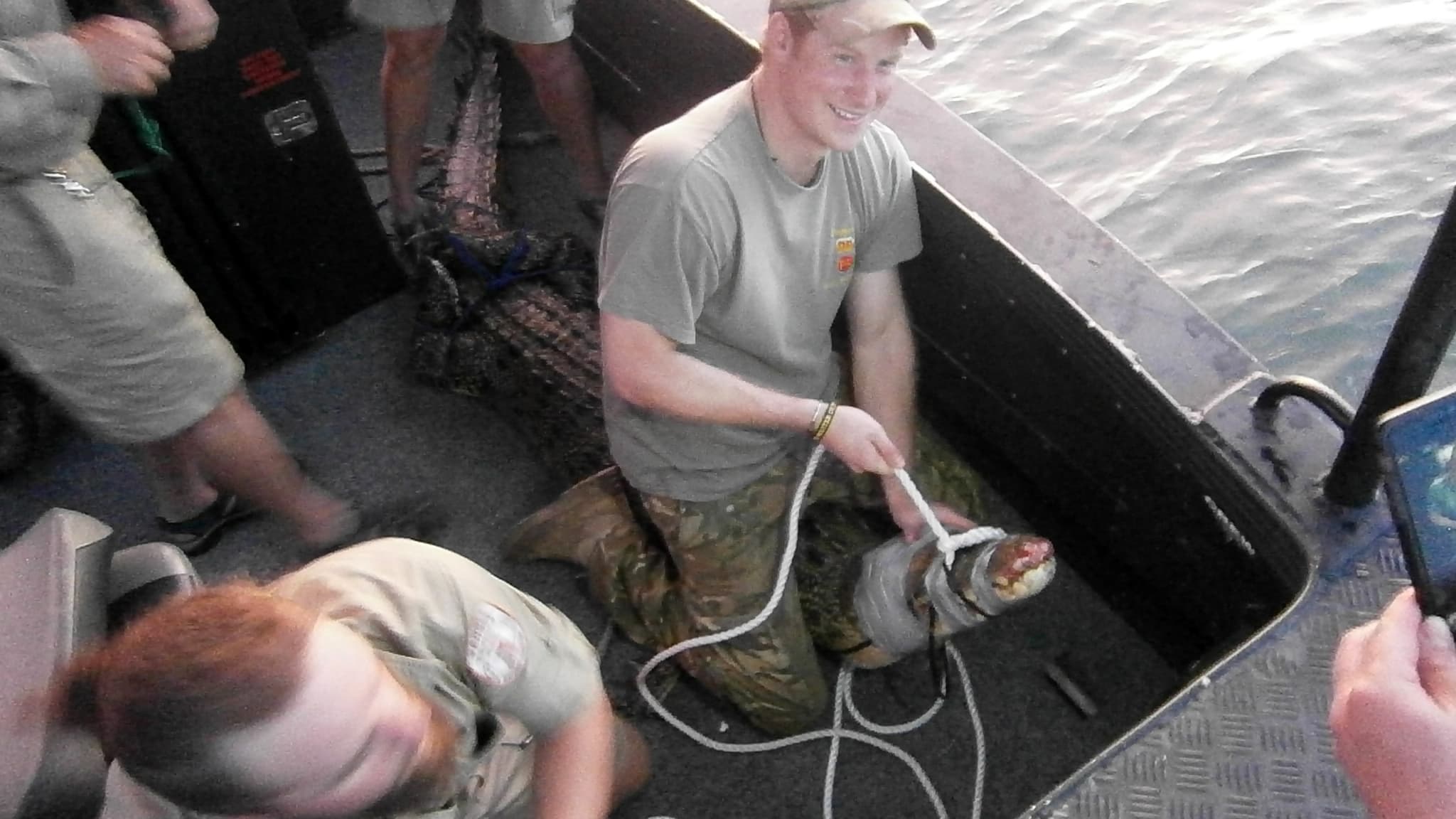 Le prince Harry assis fièrement sur le crocodile qu'il vient de capturer.