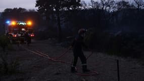Un pompier déploie un tuyau  près d'un incendie à Frontignan, dans l'Hérault, le 18 août 2024 