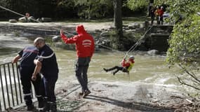 Des pompiers traversent un cours d'eau pour restaurer l'accès à l'eau potable après l'effondrement d'un pont détruit par la tempête Domingos, le 5 novembre 2023 à Corte, en Corse  